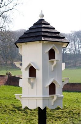 a white and black bird house sitting on top of a green field