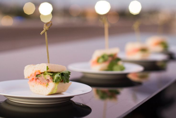 several small sandwiches on white plates with toothpicks sticking out of the top one