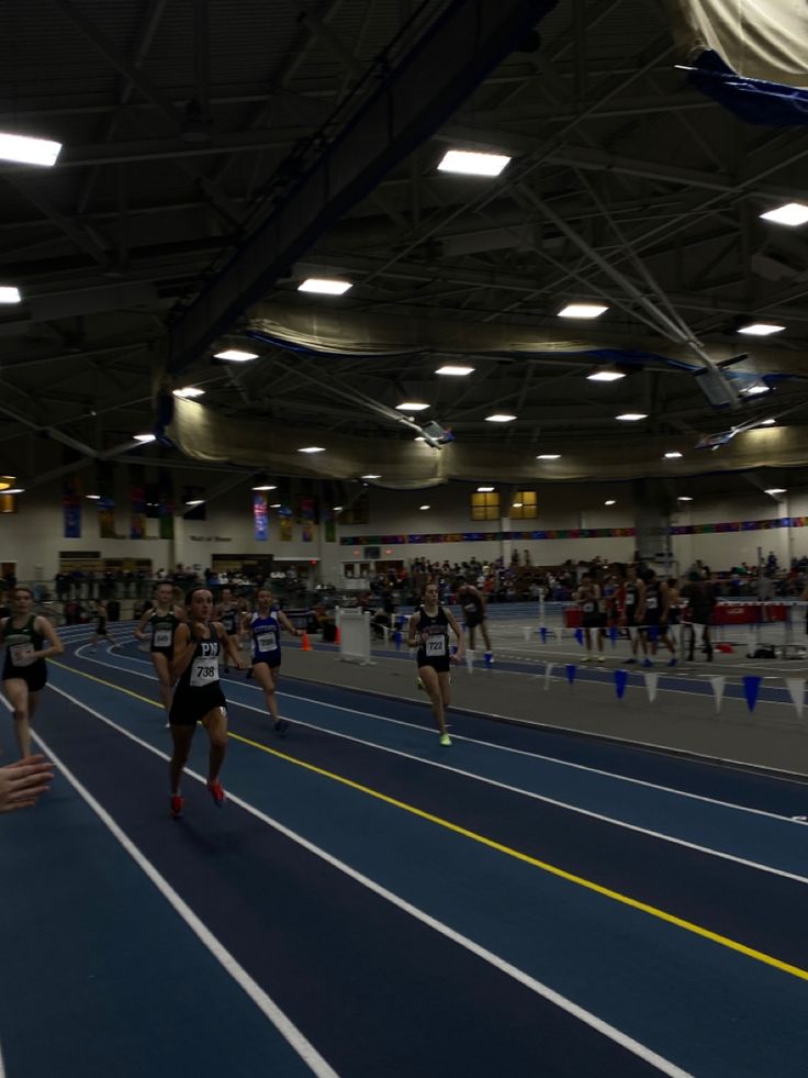 people are running on a track in an indoor stadium