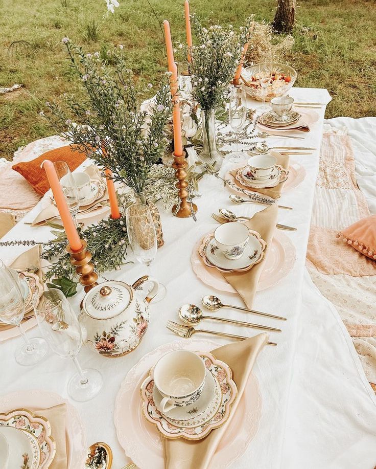 an outdoor table set with plates, silverware and candles