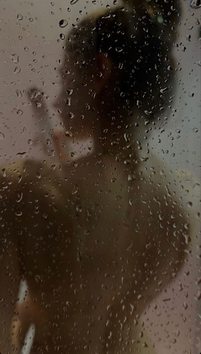 a man standing in front of a window covered in rain