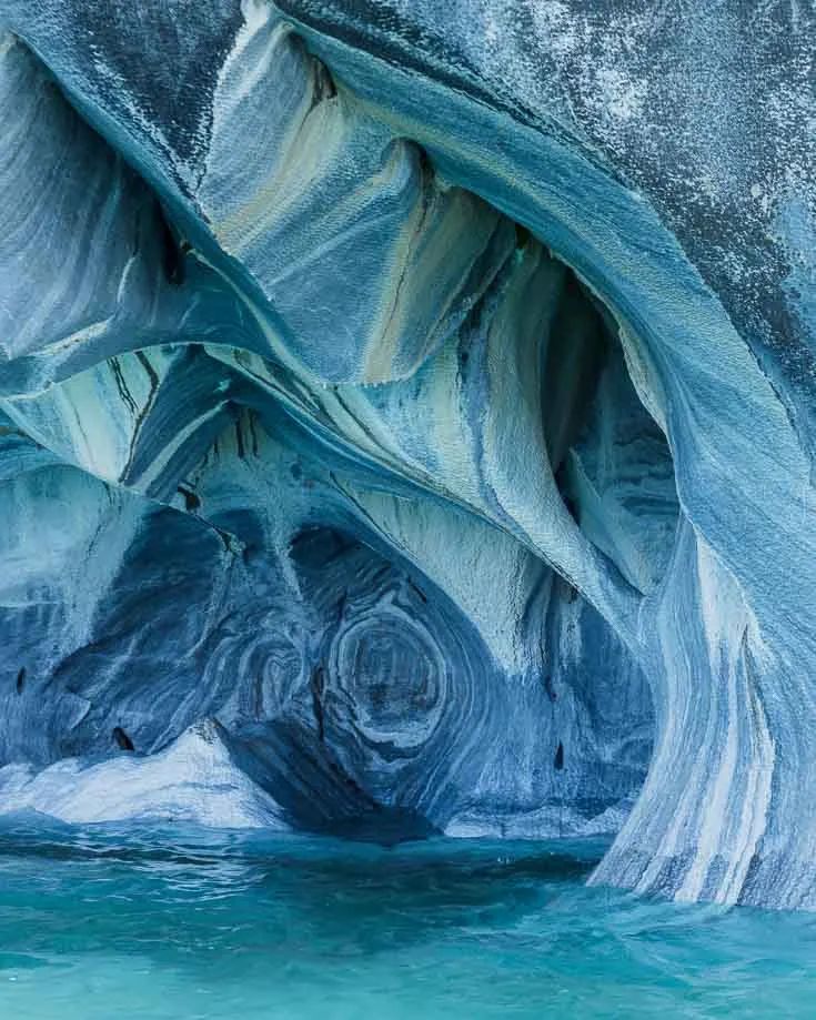 the inside of an ice cave with blue water and large rock formations on it's sides