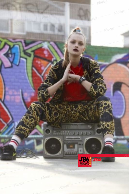 a woman sitting on top of a boombox in front of graffiti covered wall with her hand up to her mouth