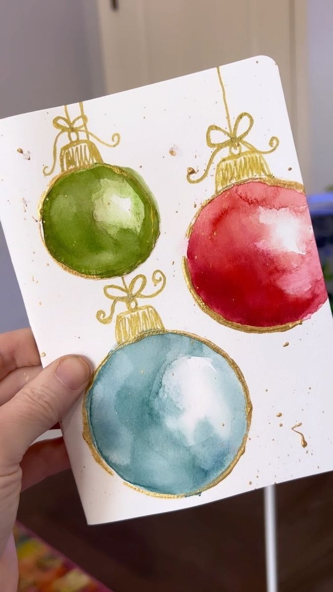 a hand holding up a card with three ornaments on it