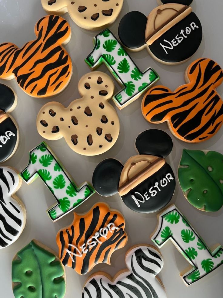 decorated cookies are arranged in the shape of mickey mouses and zebras with name written on them