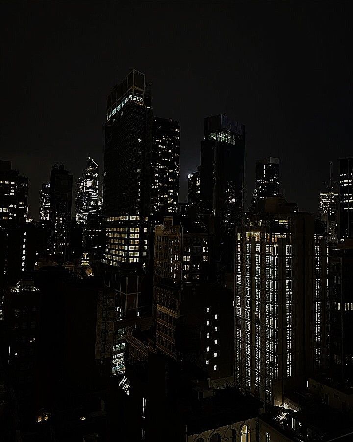 the city skyline is lit up at night, with skyscrapers in the foreground