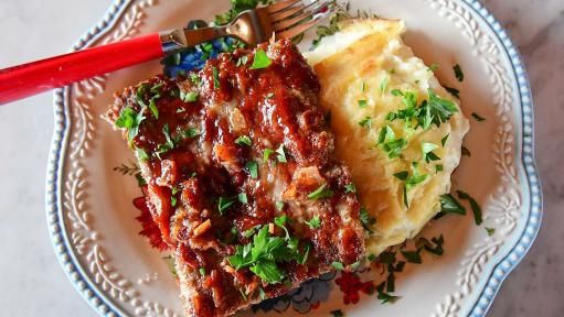 a white plate topped with lasagna and mashed potatoes next to a fork