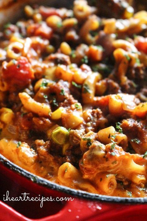 a skillet filled with macaroni and cheese covered in ground beef, tomato sauce and parsley