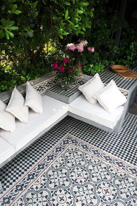 four white pillows sitting on top of two couches in front of some plants and flowers