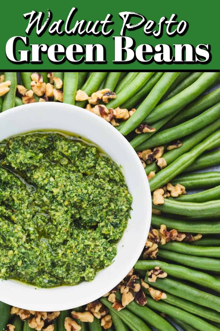 a white bowl filled with green beans and walnut pest on top of some green beans