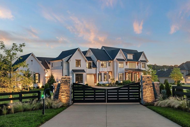 a large white house with lots of windows on it's front yard and driveway