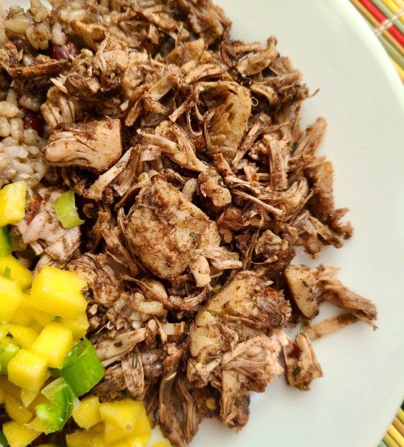 a white plate topped with meat and rice next to sliced pineapples on a table