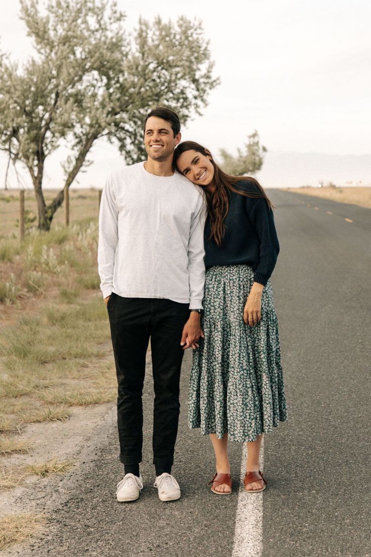 a man and woman standing in the middle of an empty road