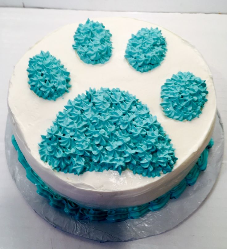 a white cake with blue frosting and paw prints on the top is sitting on a table