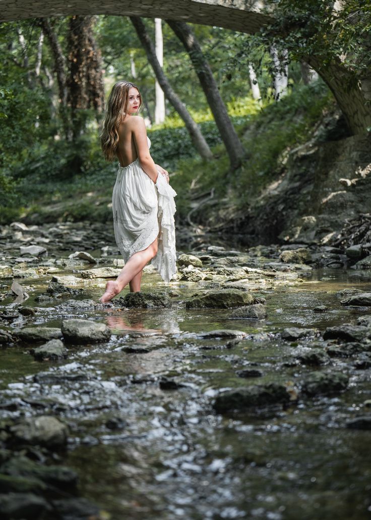 a woman is standing in the middle of a stream