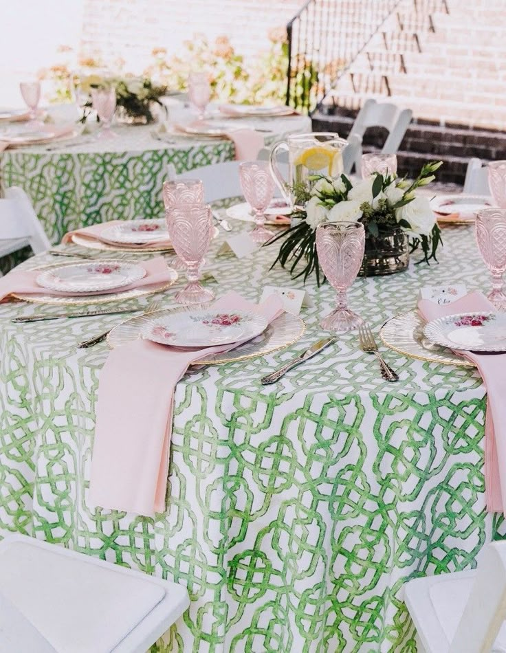 the table is set with pink and green place settings