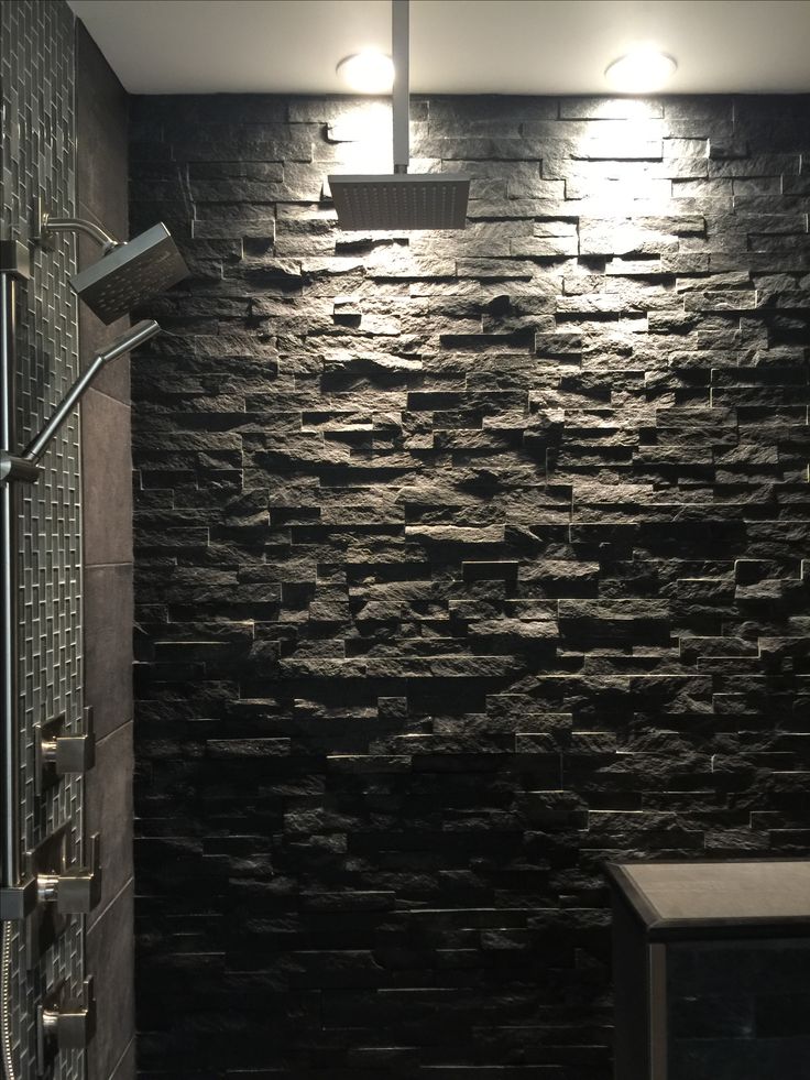 a bathroom with black stone walls and lights on the ceiling, along with a walk in shower