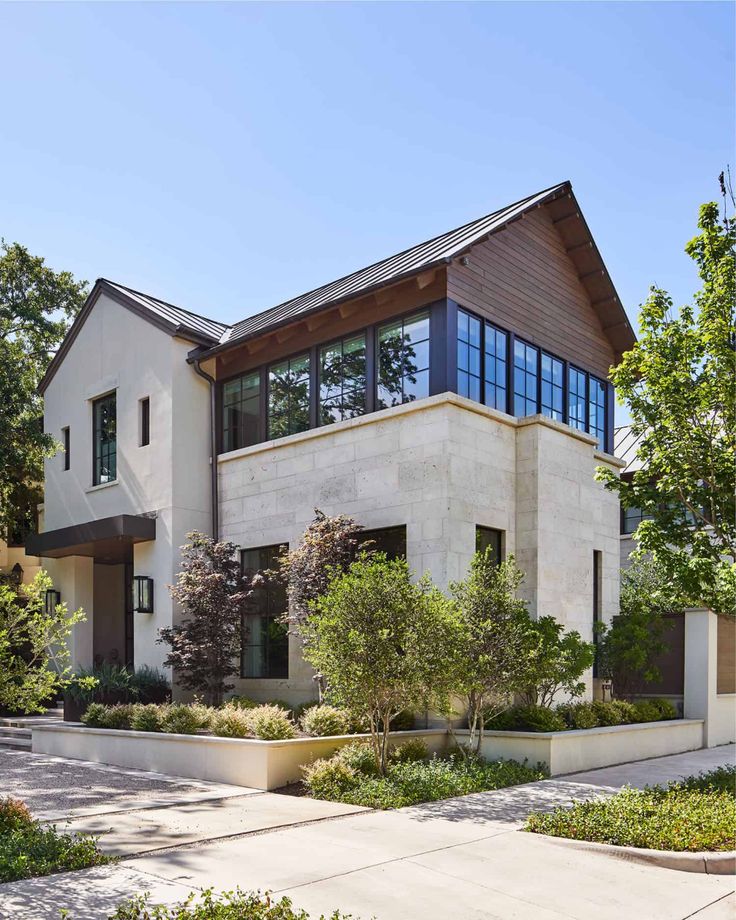 a large white house with lots of trees and bushes around it's front entrance