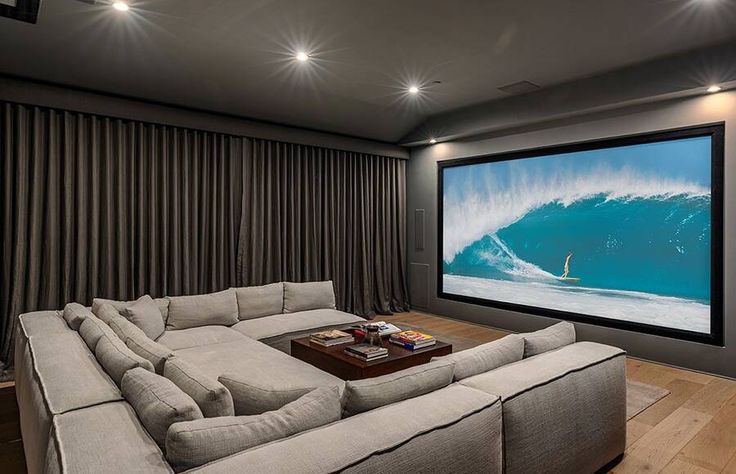 a living room with couches and a large screen on the wall in front of it