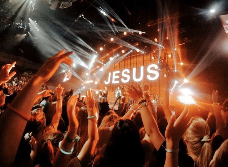 a crowd of people at a concert with their hands in the air and lights on