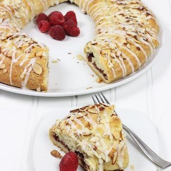 a white plate topped with a cake covered in frosting and raspberries