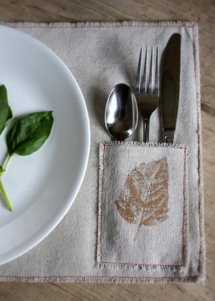 a white plate and silverware on top of a placemat with a leaf design