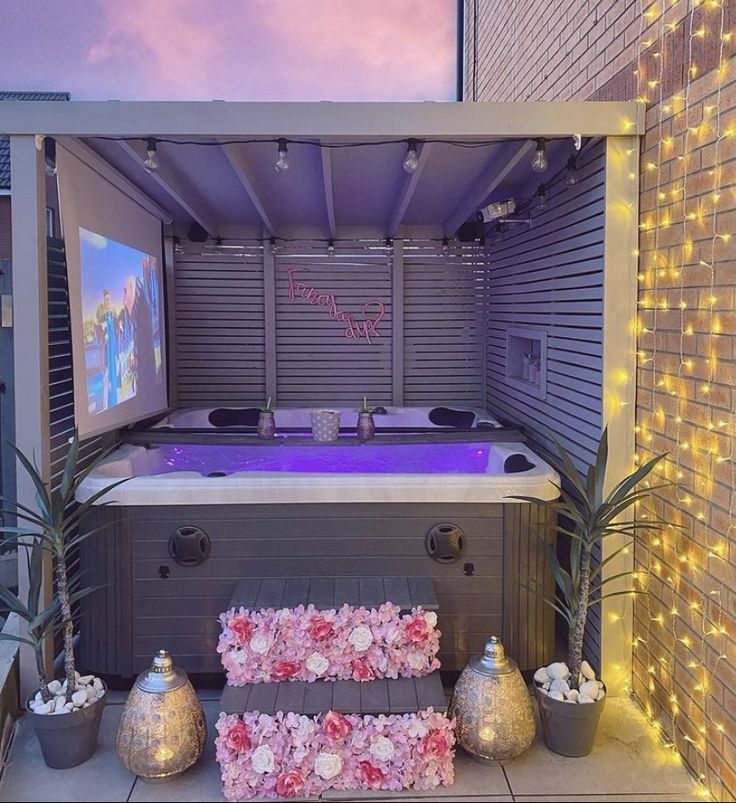 an outdoor hot tub with flowers and lights around it