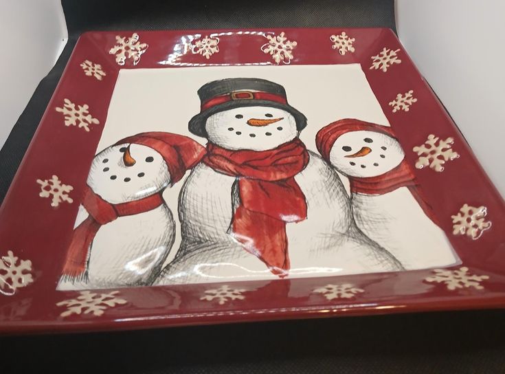 a red tray with three snowmen on it