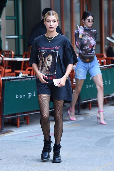 a woman walking down the street in short shorts and black shirt with an image on it