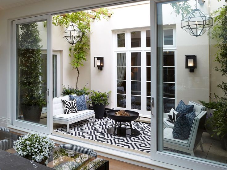 a living room filled with lots of furniture and plants on the windows sills