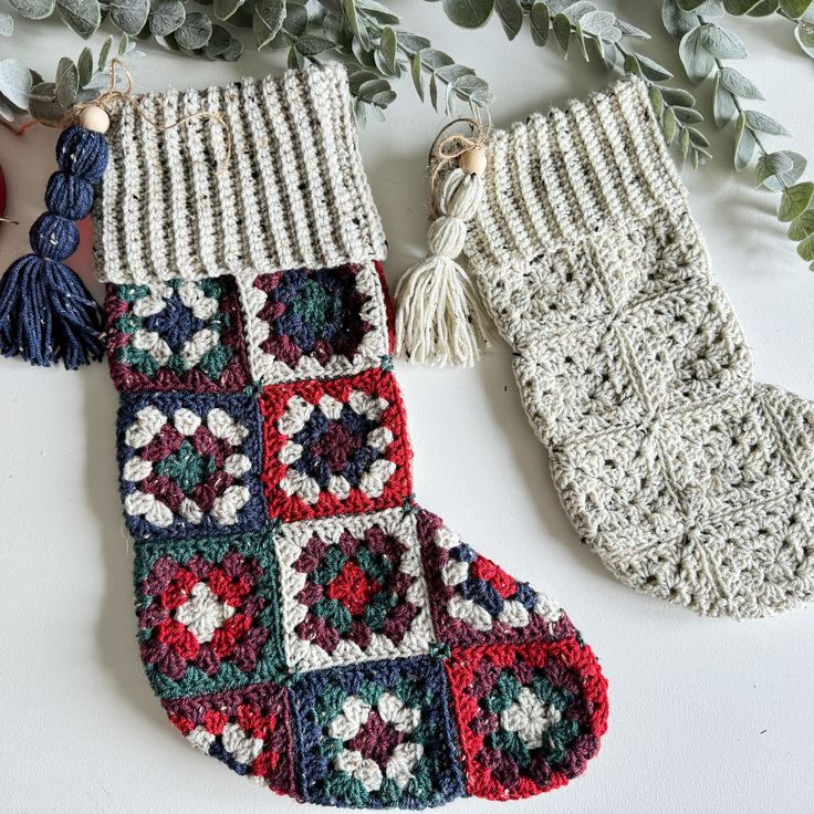 two crocheted christmas stockings with tassels hanging from them on a table