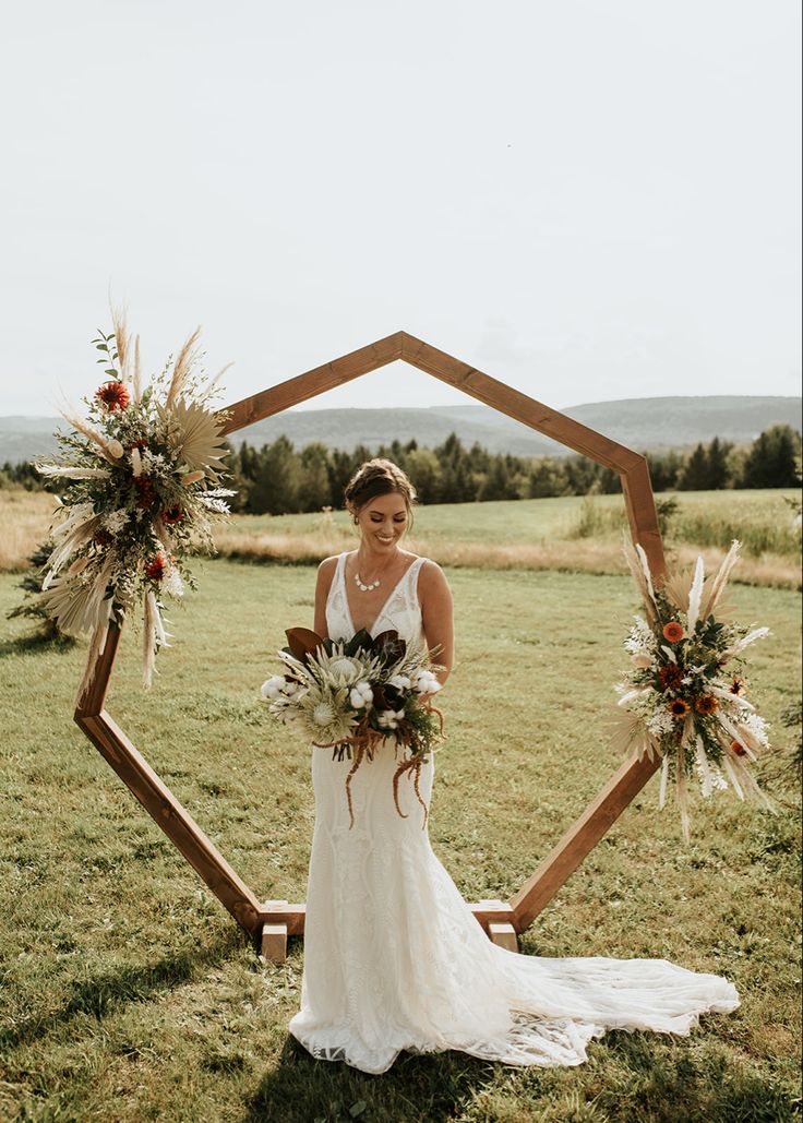 a woman standing in front of a wooden frame holding flowers