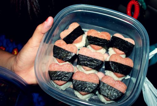 a person holding a container filled with sushi