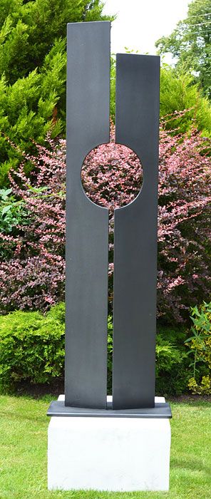 a large metal sculpture sitting on top of a lush green field