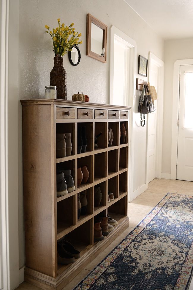 there is a shoe rack with many pairs of shoes on it in the entryway