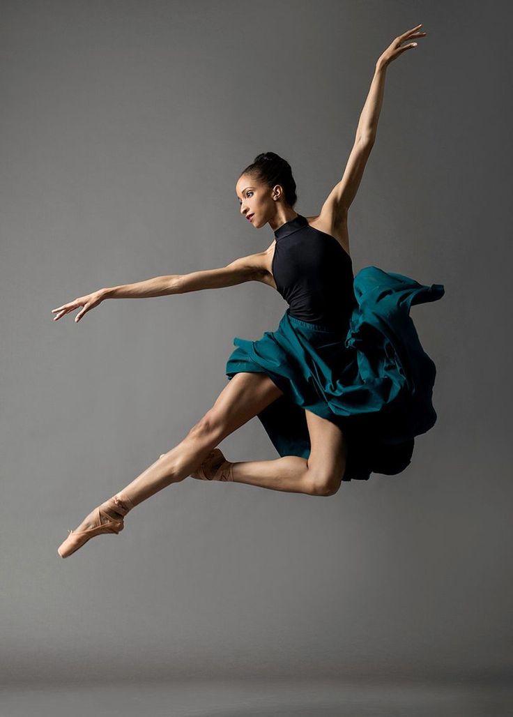 a woman in black shirt and blue skirt doing a dance move with her legs spread out