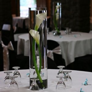 a vase filled with white flowers on top of a table next to two wine glasses