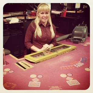 a woman sitting at a casino table with her hands in the slots on it