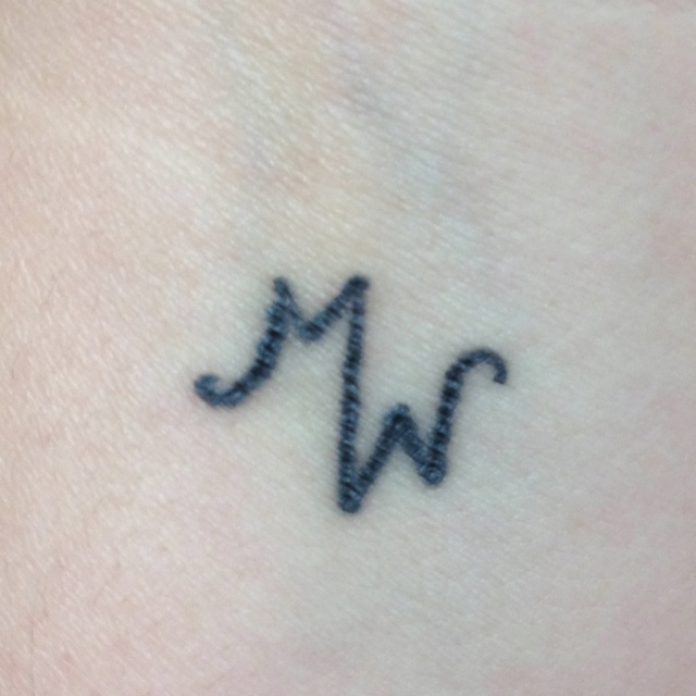 a small tattoo on the back of a woman's arm that reads m and w