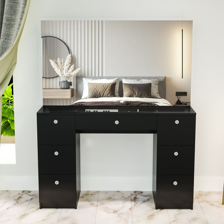 there is a black desk with drawers in front of the bed and mirror on the wall