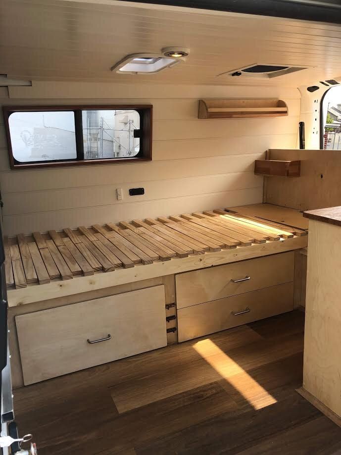 the inside of a camper with wooden flooring and storage drawers on each side