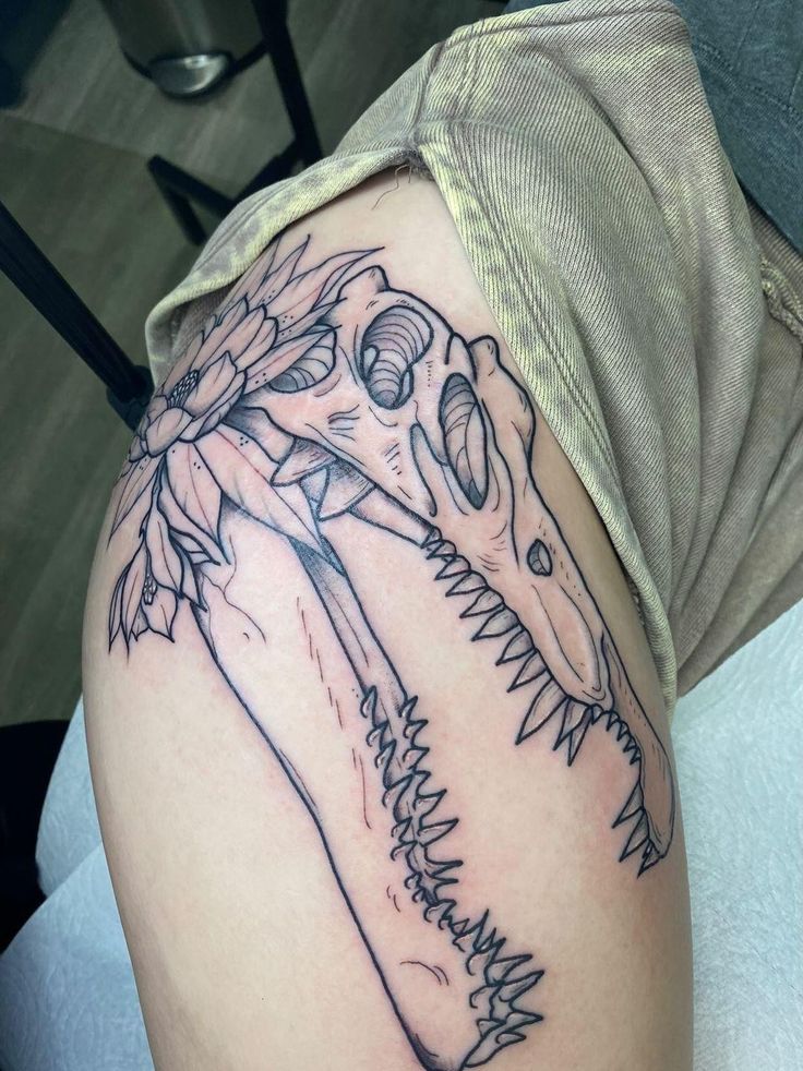 a close up of a person's arm with a dinosaur tattoo on it