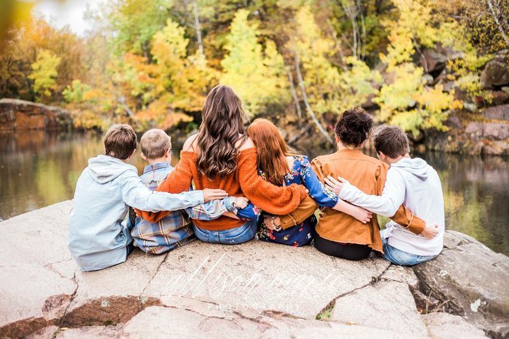 a group of people sitting on top of a rock next to a body of water