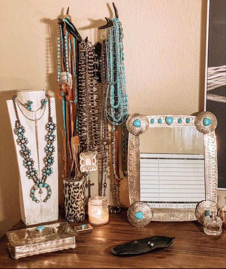 an assortment of jewelry is displayed on a table with a mirror and other items next to it