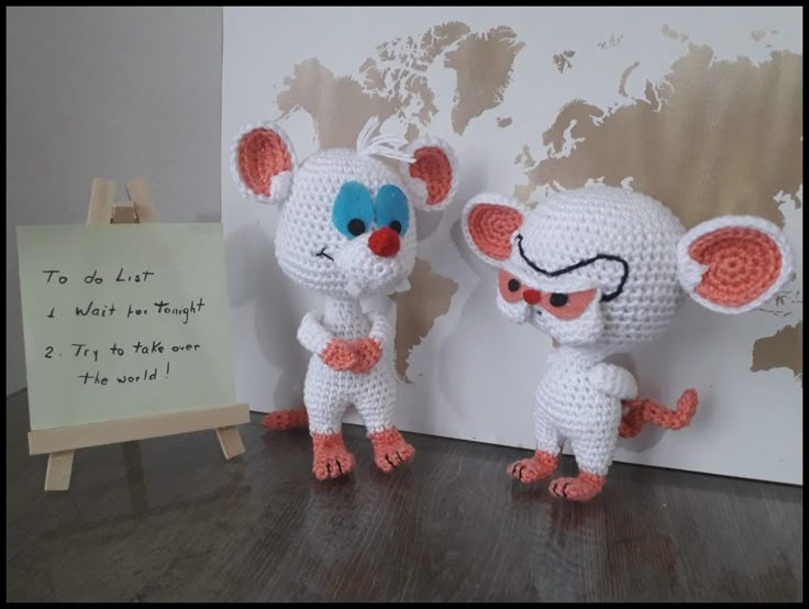 two crocheted mice standing next to each other in front of a world map