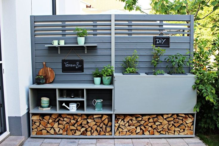 an outdoor firewood storage unit with potted plants