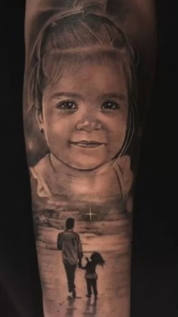 an arm tattoo with a photo of a child on it