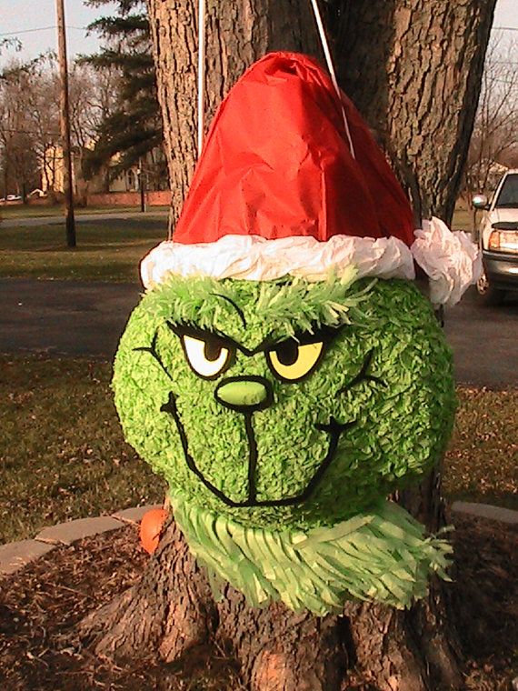 a green tree with a red santa hat on it's head sitting in the middle of a park