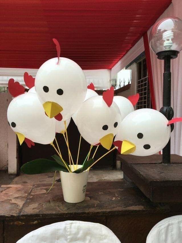 a bunch of balloons that have been placed in a vase with chicken heads on them