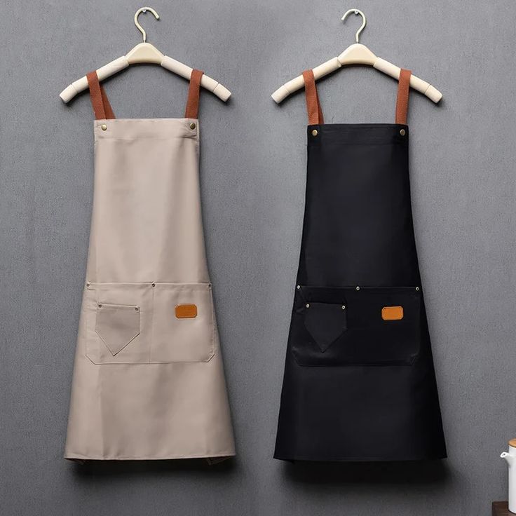 two aprons are hanging on the wall next to each other, one is black and tan